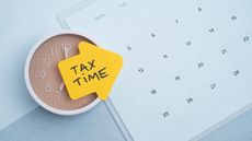 Tax time concept. Reminder sticker on clock and calendar background