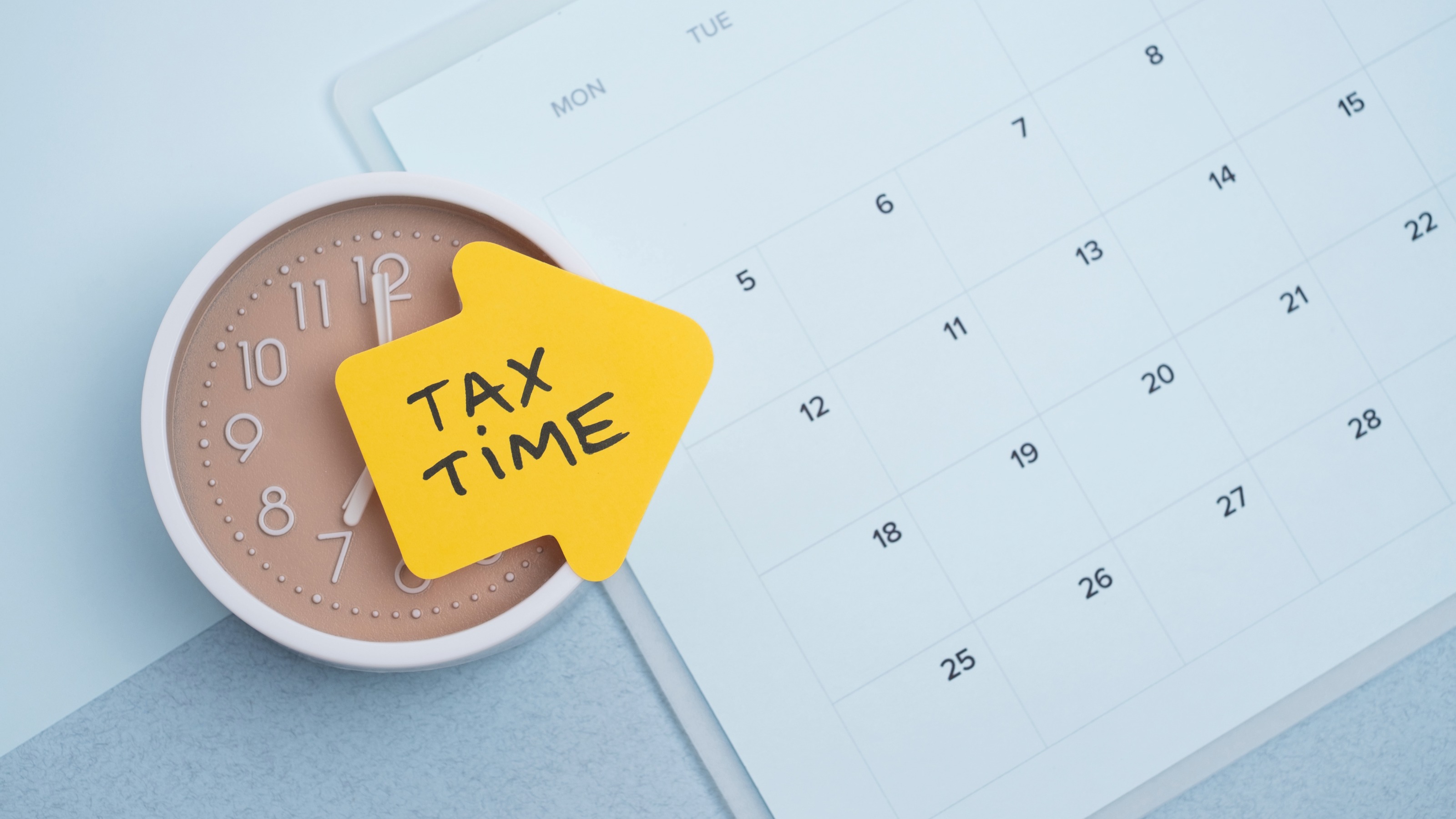 Tax time concept. Reminder sticker on clock and calendar background