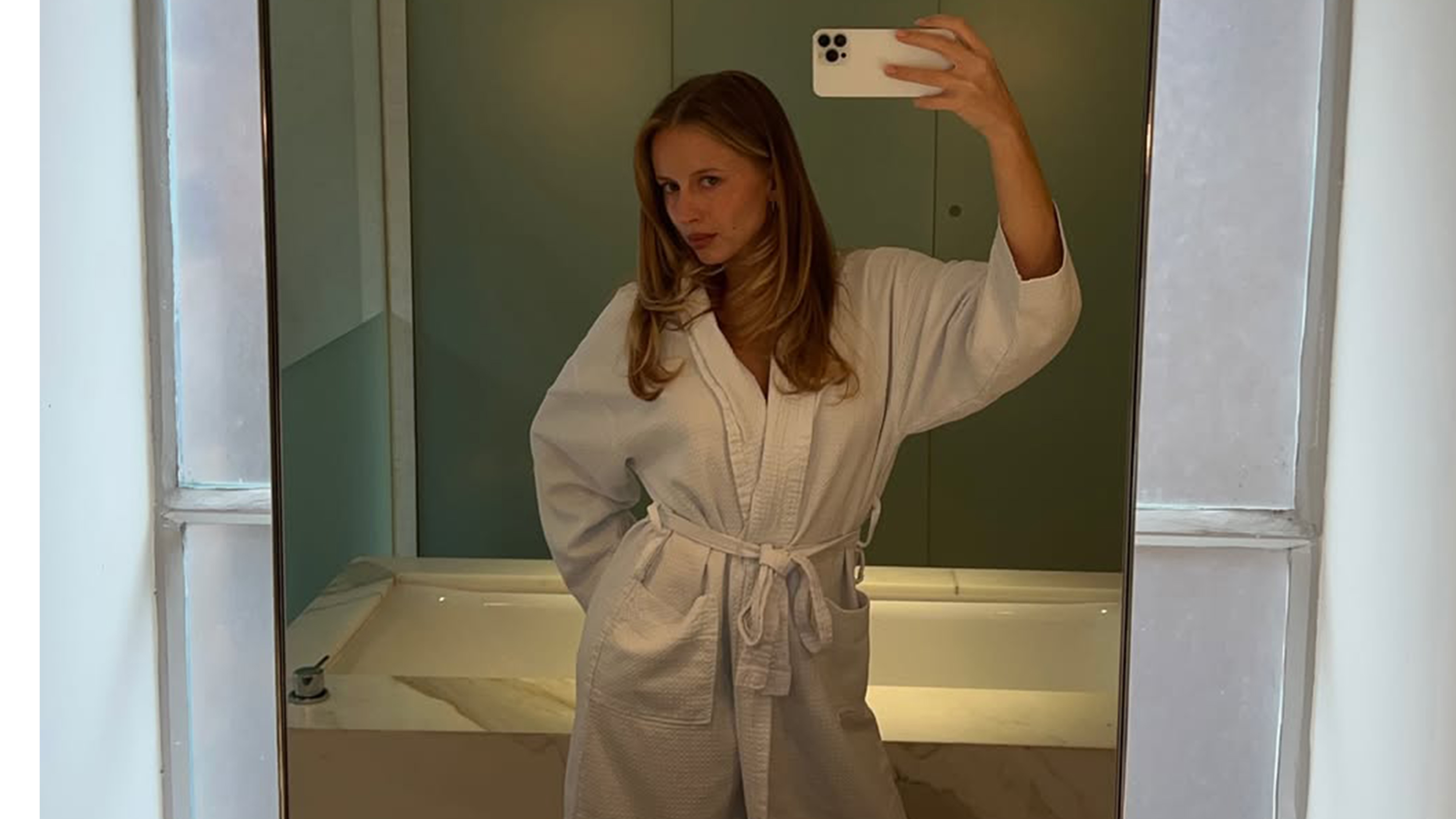 Hannah Juneva taking a mirror selfie in a bath robe.