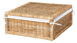 A light brown lidded rattan storage basket with a white inside fabric that ties on around the basket's corners, for the best ornament storage containers.