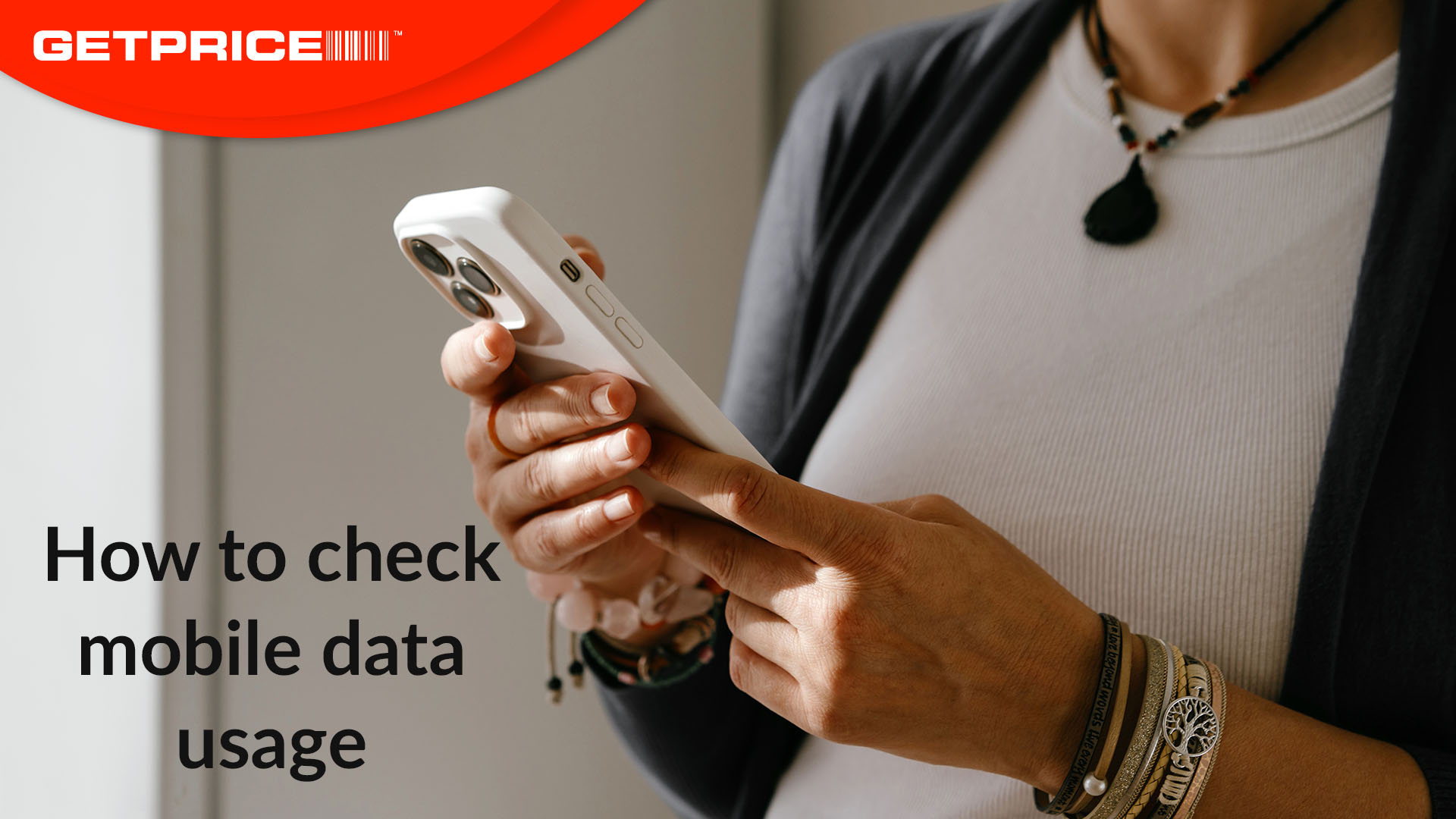 Person holding mobile phone and looking at it with red GetPrice logo in top left corner and black text that says How to check mobile data usage