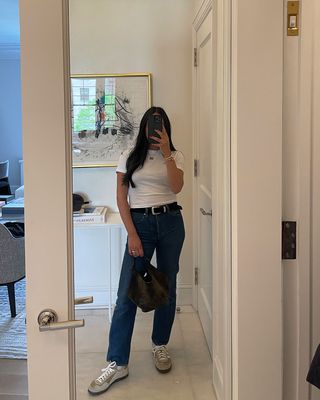 A woman taking a mirror selfie and holding a Khaite Lotus tote.