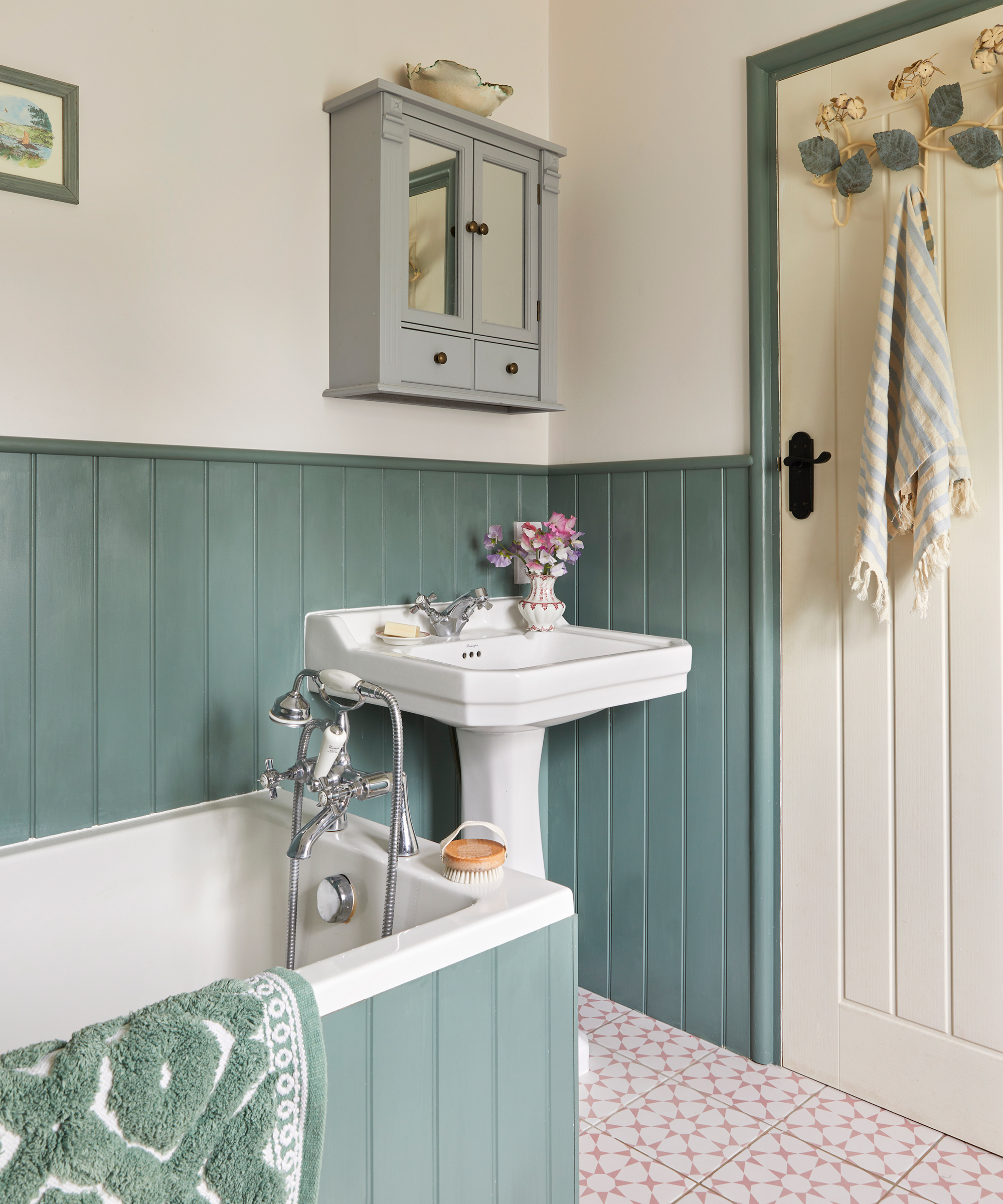 Cottage bathroom with green wall and bath panelling, cream walls and pink and white star floor tiles