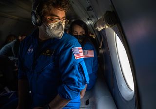 Bill Spetch (left), the Manager of NASA's ISS Transportation Integration Office, and Courtney Beasley, a NASA Public Affairs Officer, look out the window of an AN-26 aircraft as they fly from Karaganda to Zhezkazgan, Kazakhstan to prepare for the Soyuz MS-17 landing of Expedition 64 crew members Kate Rubins of NASA, Sergey Ryzhikov and Sergey Kud-Sverchkov of Roscosmos on April 16, 2021.