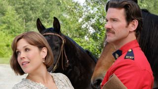 Elizabeth and Nathan stand in front of two horses
