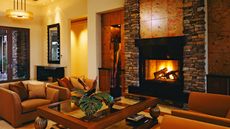 Contemporary stone fireplace in modern living room with warm orange, brown and yellow color scheme