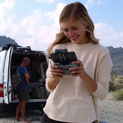 gabby petito looking at a game device outside of her van smiling in a still from the american murder documentary