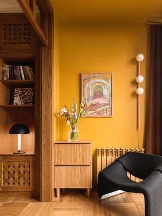 A living room with ochre walls and a black chair