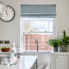White kitchen with window and blue blinds behind sink