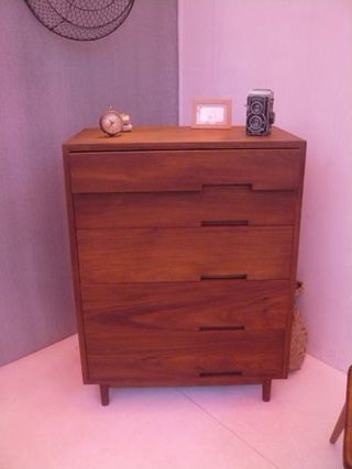 A lilac room with a wooden chest of drawers featuring offset handles