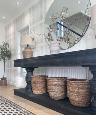 A white entryway black console table with woven baskets underneath