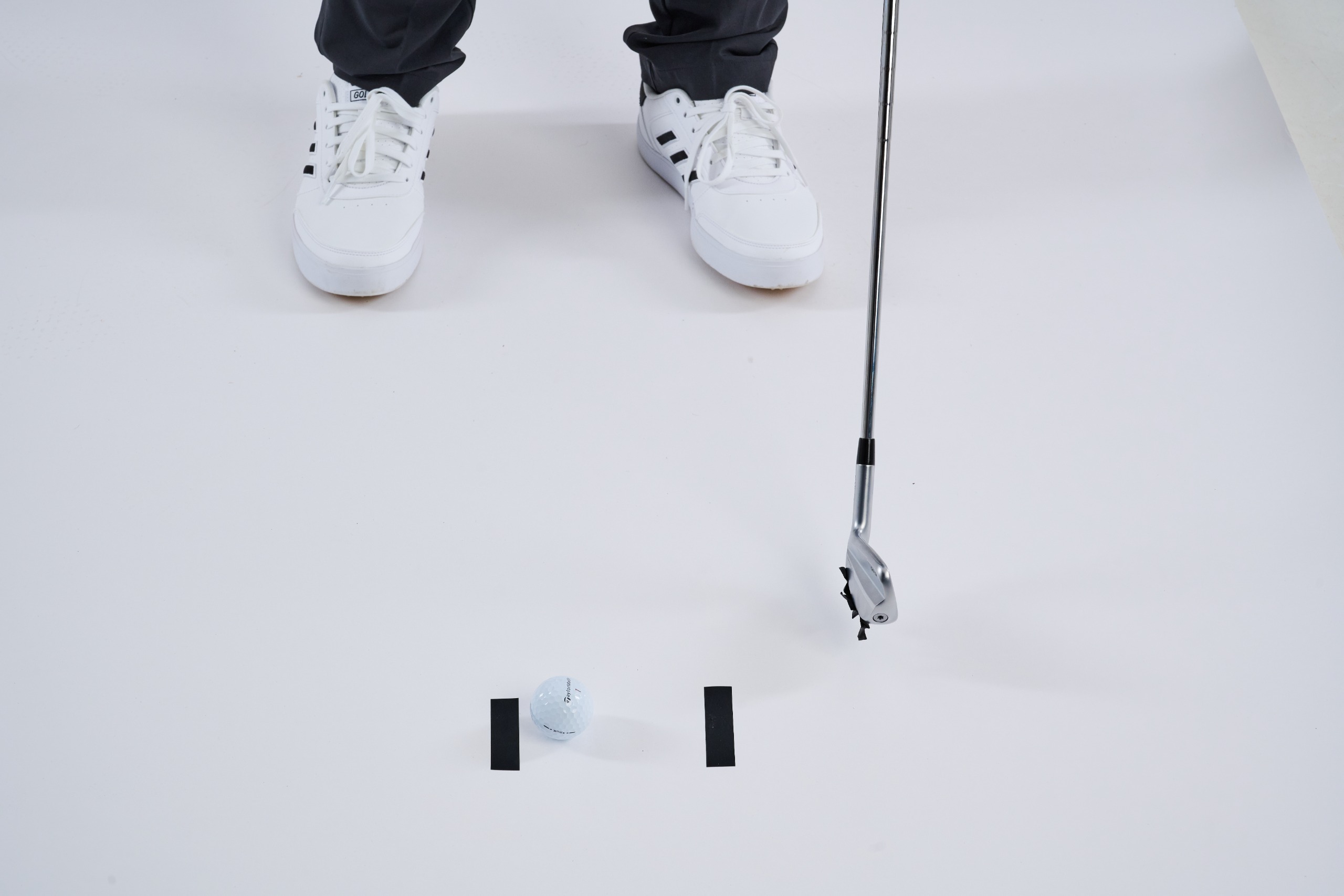 A club with a piece of sticky tape attached to the bottom after striking it at impact, with the two other pieces of tape unaffected on the ground