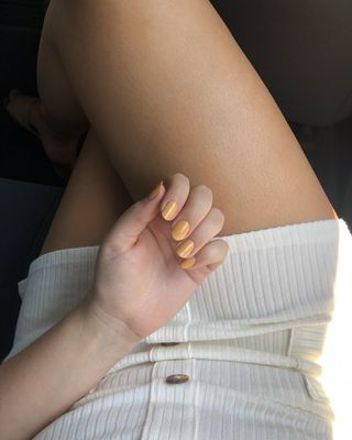 Beauty editor Kaitlyn McLintock's hand wearing gold nail polish
