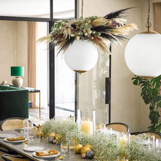 Dining table decorated with foliage and pendant light with dried flowers