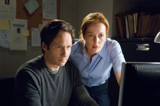 mulder and scully look at a computer screen in a still from the x files