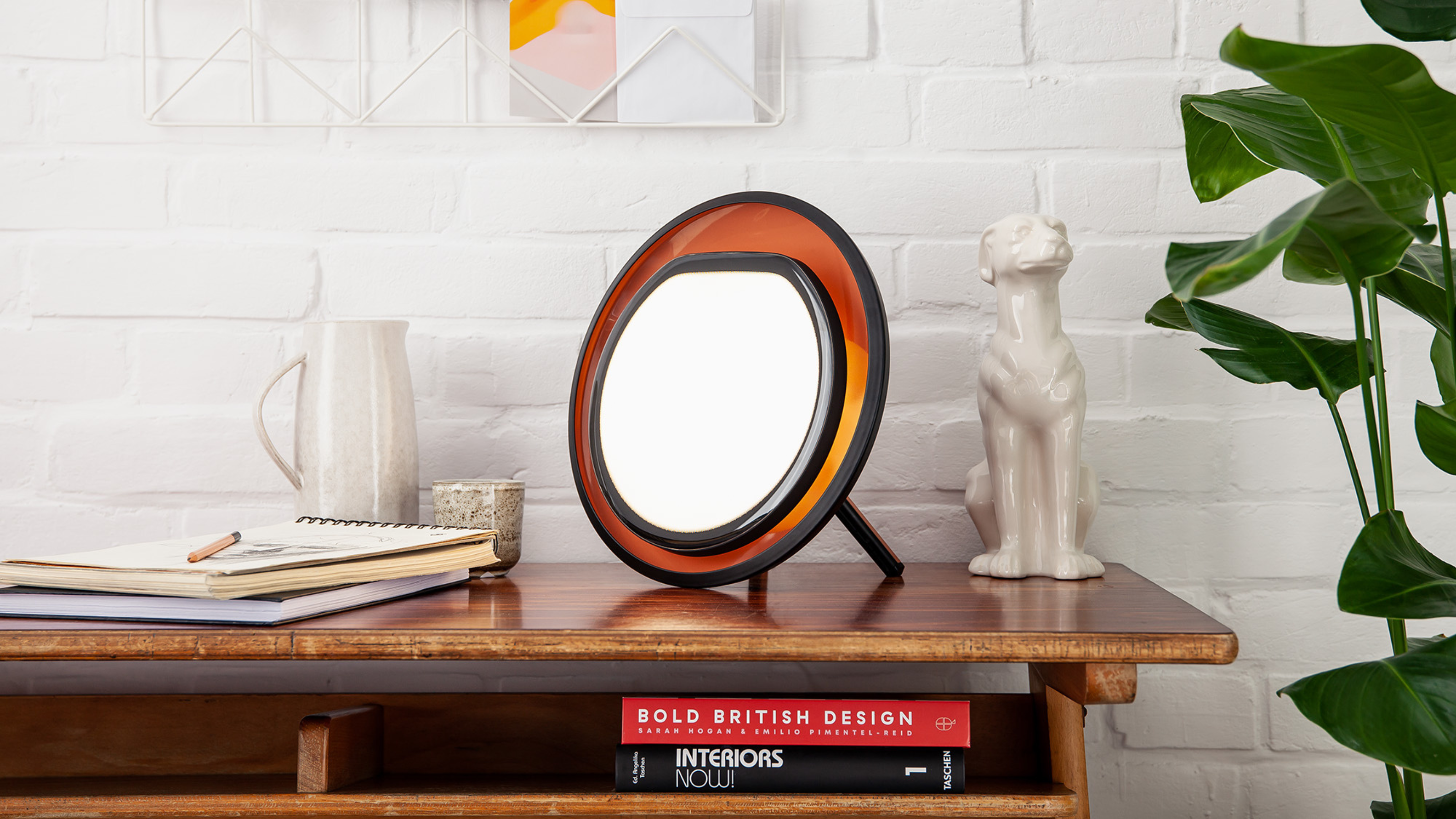 the lumie halo lamp sat on a wooden shelf with other art objects