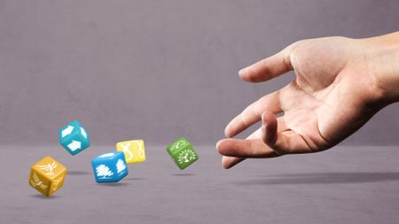 Hand rolling dice marked with logos of British political parties, including Conservative, Green, Reform UK, SNP and Liberal Democrat