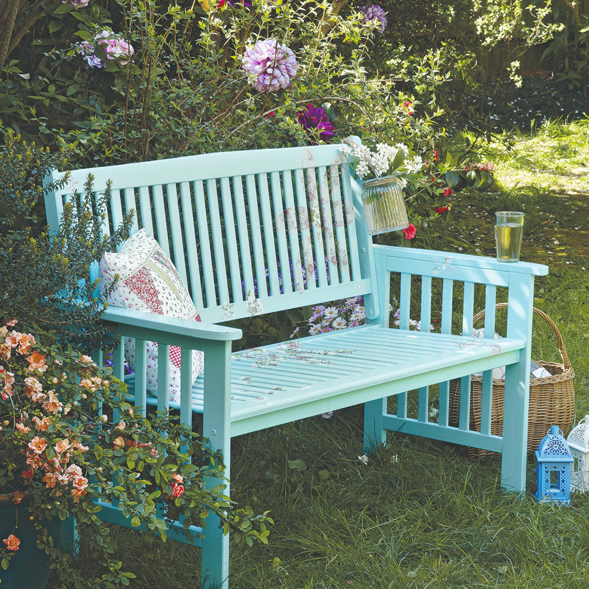 A turquoise-painted garden bench surrounded by flowering plants