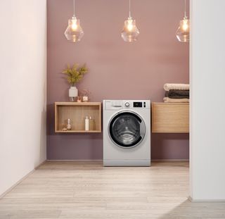 blush pink toned utility room with wooden cabinets and hotpoint washing machine available from AO