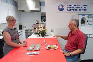 Vickie Kloeris (left), NASA food scientist and manager of the Space Food Systems Laboratory at the Johnson Space Center, and astronaut Mike Massimino discuss the items on the special American meal. Massimino served as a taste tester for the space feast.