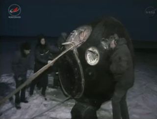 Russian recovery workers roll the Soyuz TMA-05M capsule that landed on Nov. 18, 2012 ET into position to retrieve three Expedition 33 crewmembers