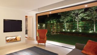 contemporary garden room with bi-fold doors leading onto deck and garden lighting
