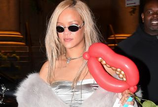 Rihanna wearing a silver bustier and gray fur vest.