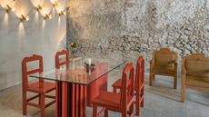 tables and chairs by Alekos Fassianos in front of bare stone walls