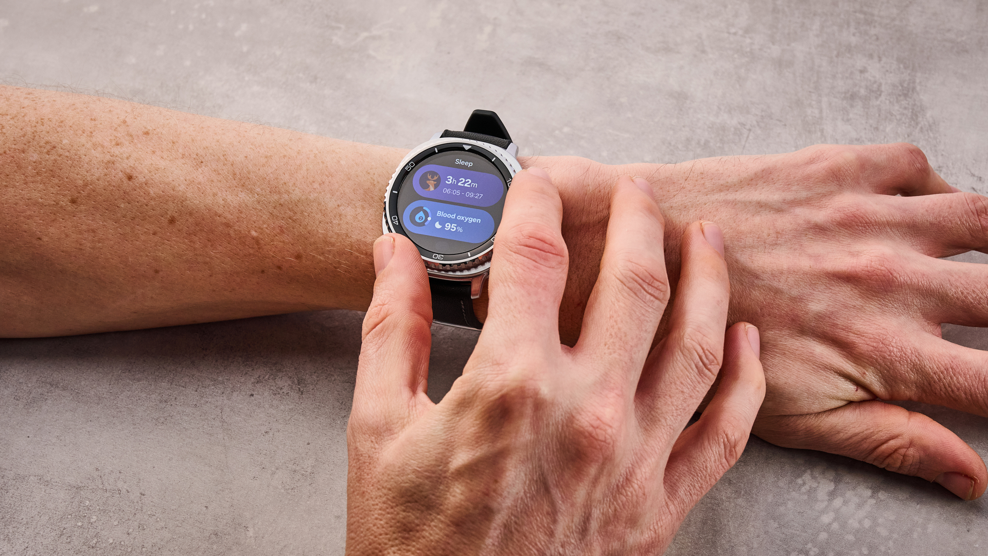 The Samsung Galaxy Watch 8 Classic on a man's wrist; he turns its dial to select its sleep features.