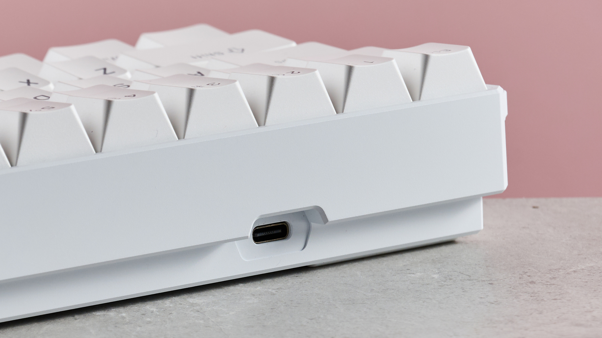 Close-up of USB-C port on MonsGeek FUN60 Ultra, on desk with pink background