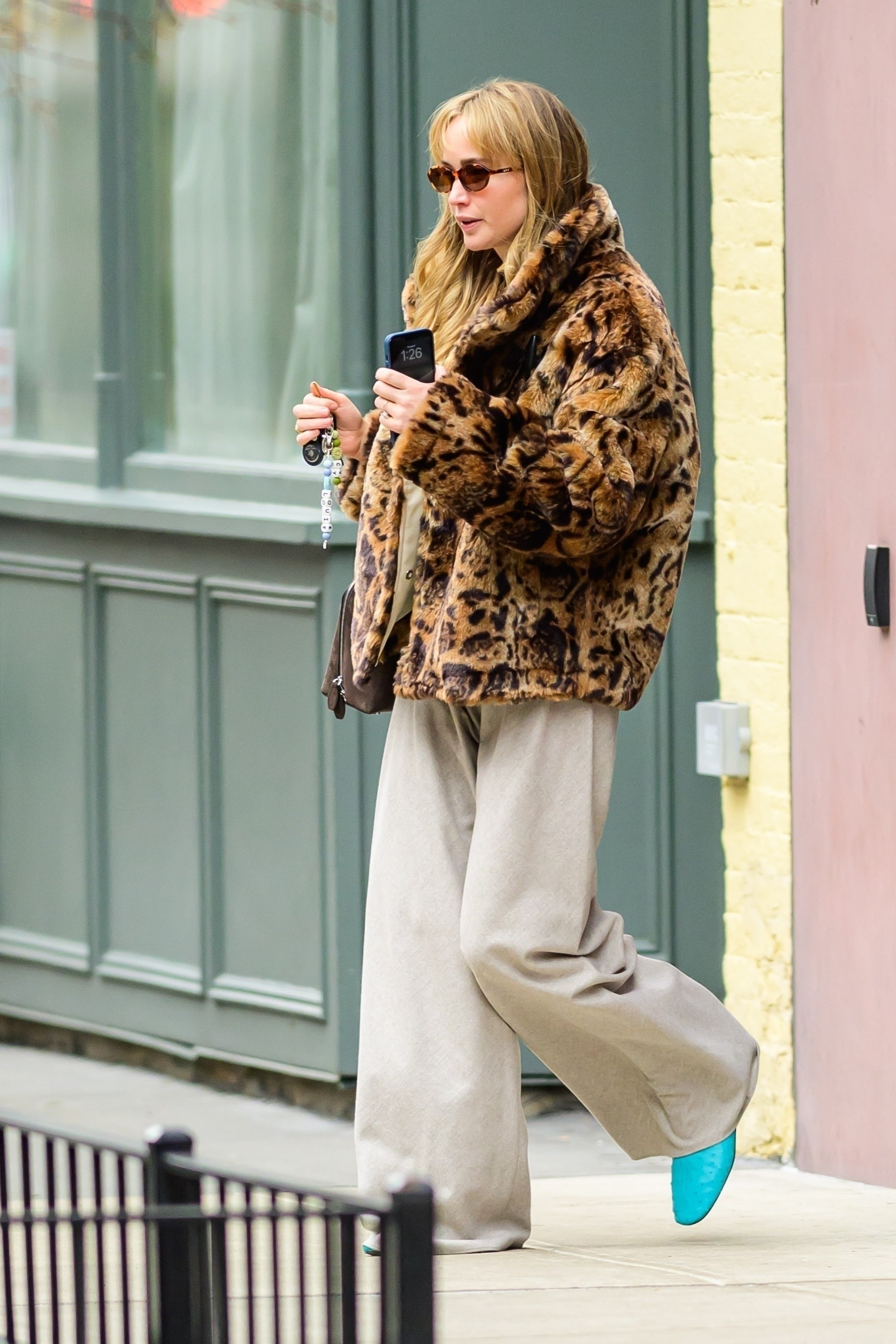 Jennifer Lawrence wears light beige track pants with a leopard print coat.