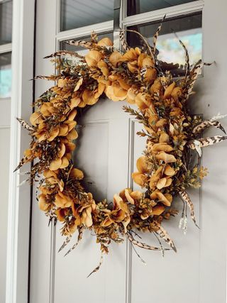 Burnt orange natural fall wreath hanging on grey door