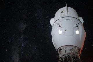 the end of a white-capped black docking port sticks up from the bottom right. Attached, a pearl-white two-windowed space capsule, with a long ribbed trunk with flat fins. In the background on the left, the milky way rises. Black space fills throughout, riddled with stars.