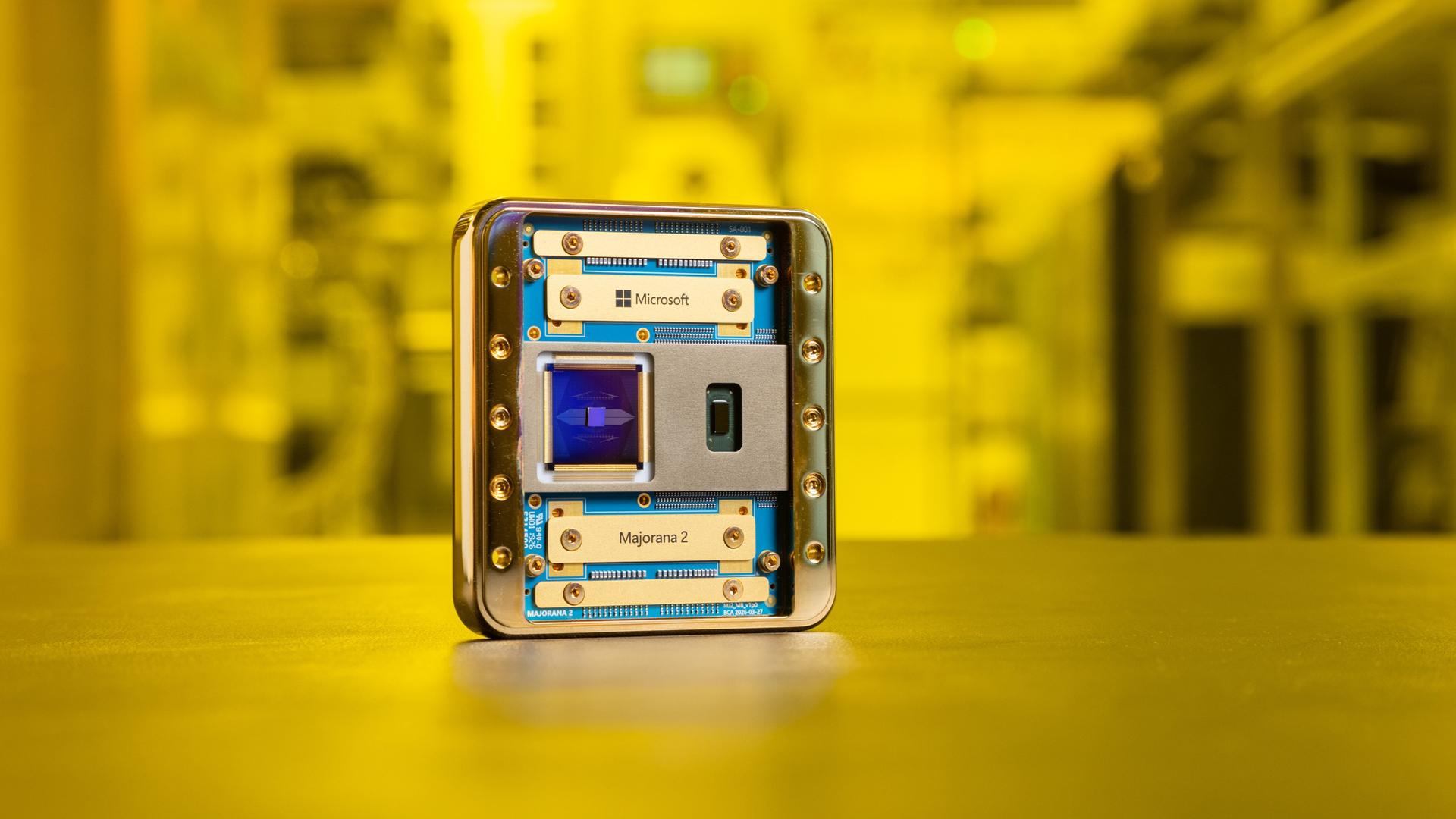 Microsoft's Majorana 2 quantum chip placed on a desk in a laboratory with yellow lighting in background.