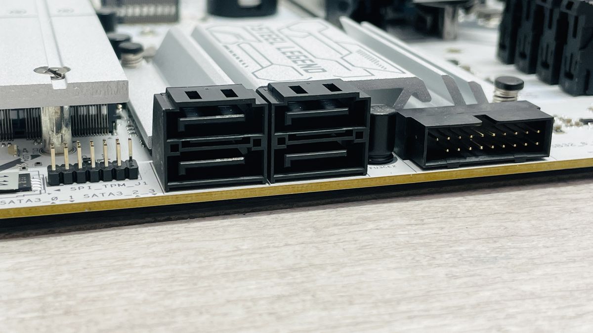 An ASRock B860 Steel Legend Wi-Fi motherboard on a desk with SSD covers removed.
