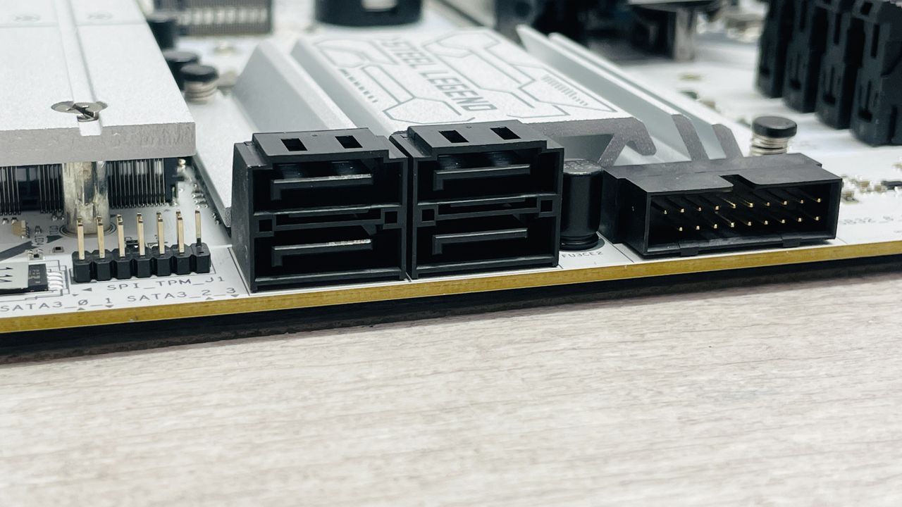 An ASRock B860 Steel Legend Wi-Fi motherboard on a desk with SSD covers removed.