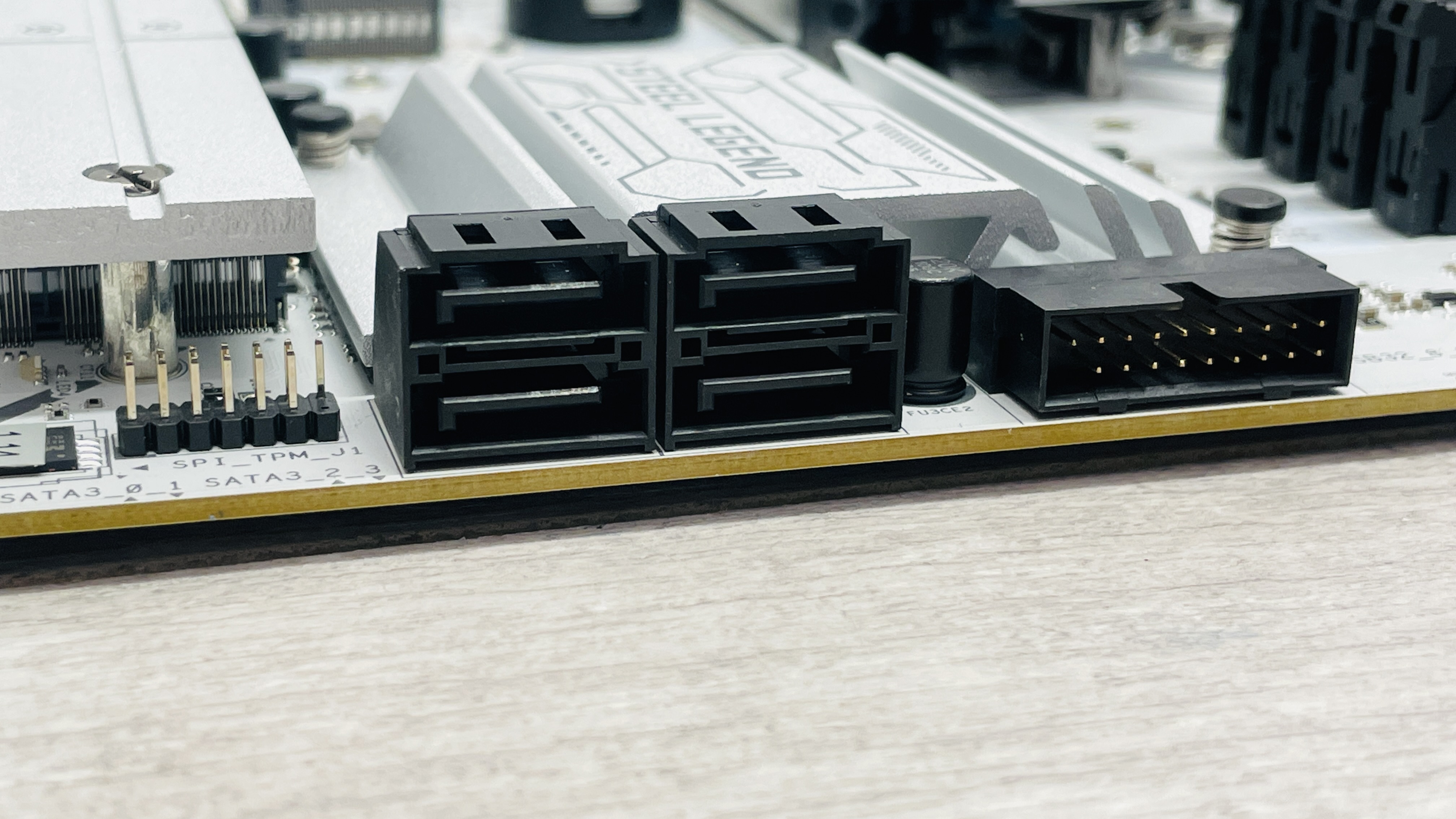 An ASRock B860 Steel Legend Wi-Fi motherboard on a desk with SSD covers removed.