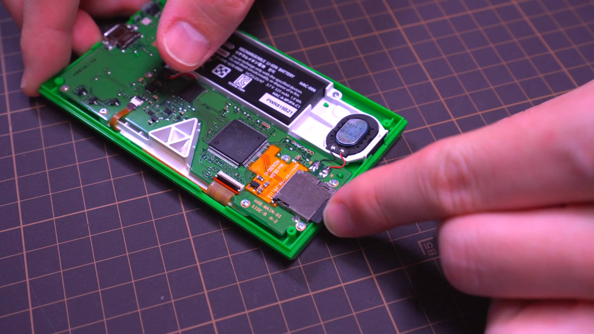 Screenshot of Macho Nacho Productions installing microSD card in modded Zelda Game and Watch with back removed.