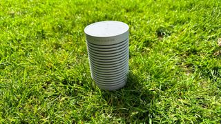 Beosound Explore Bluetooth speaker in the grass from the rear