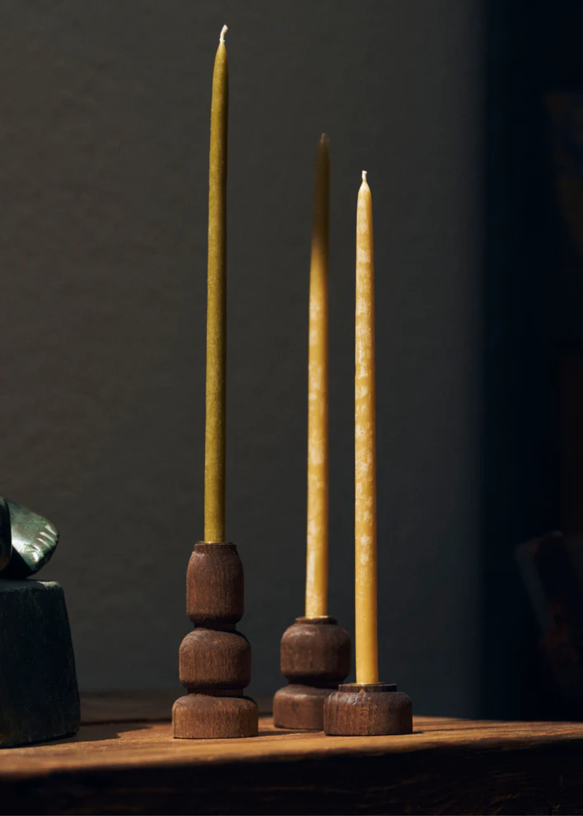 A set of three beeswax candles on wood holders
