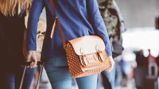 woman with crossbody bag walking through airport