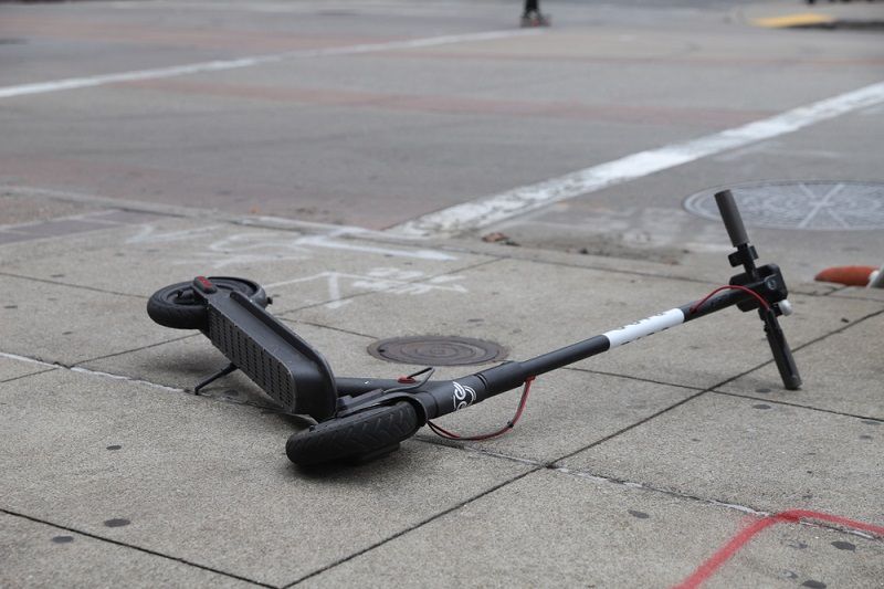 An electric scooter lying on the street.