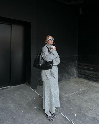 @dinahansen wears a grey knitted jumper, matching maxi skirt, chunky socks, rhinestone ballet flats and a woven leather tote bag