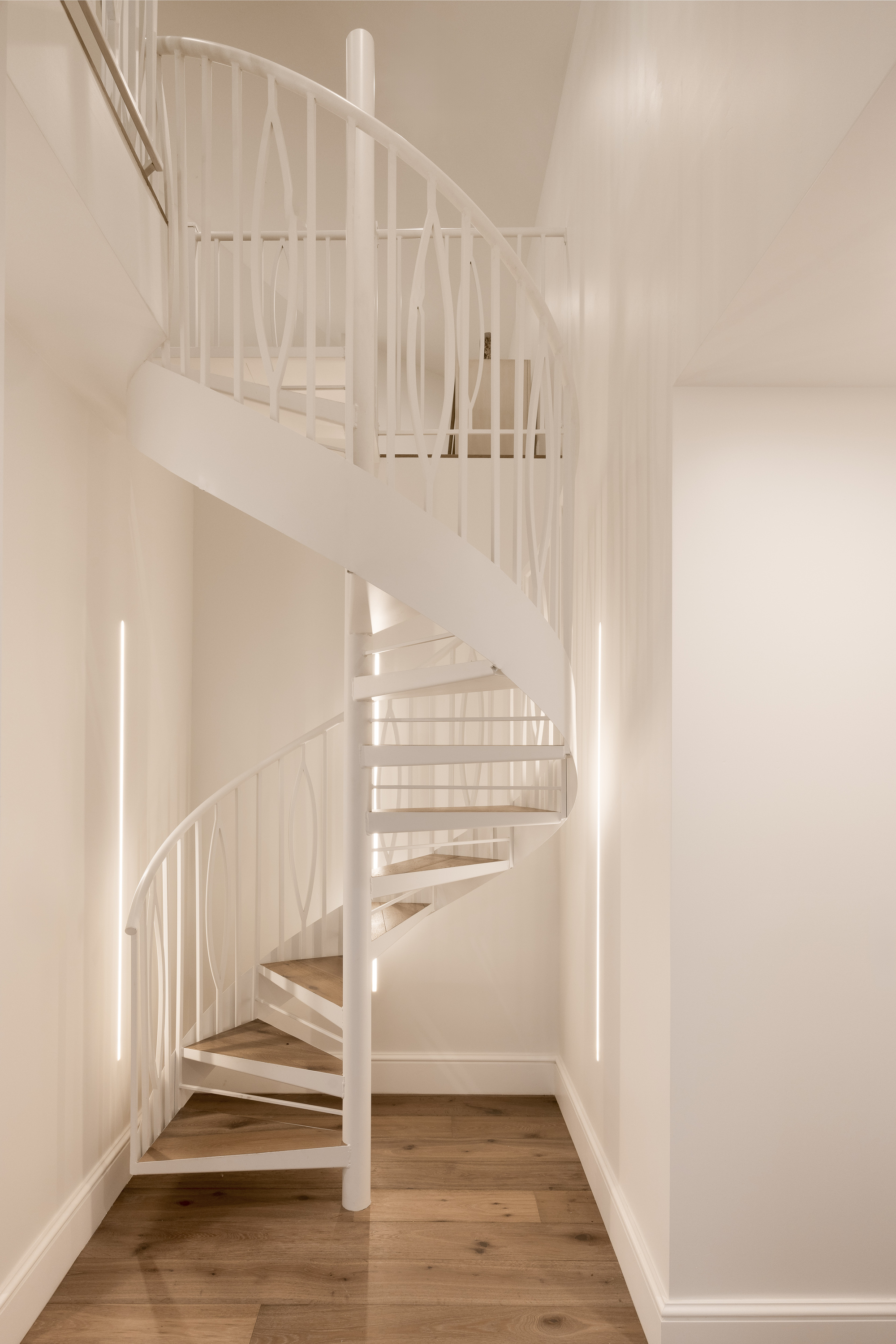A spiral staircase leading to a loft with a sculptural balustrade