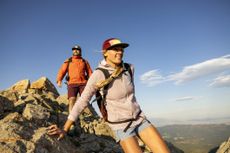 A young adult woman and man climbing down a rocky hike, happily.