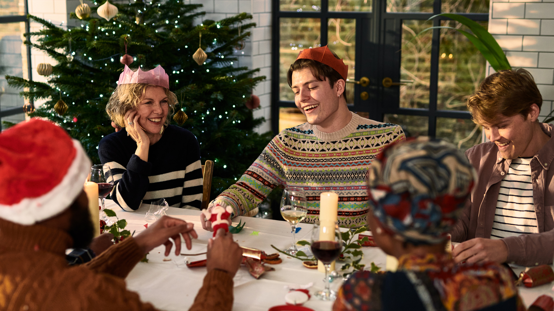 Cheerful family sitting down after Christmas dinner playing games
