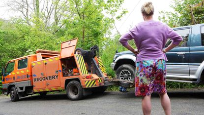 Photo of a woman watching her car being towed 