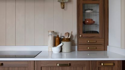 white kitchen counter tops with brown cabinets and induction hop, assorted jars of salt and other kitchen tools