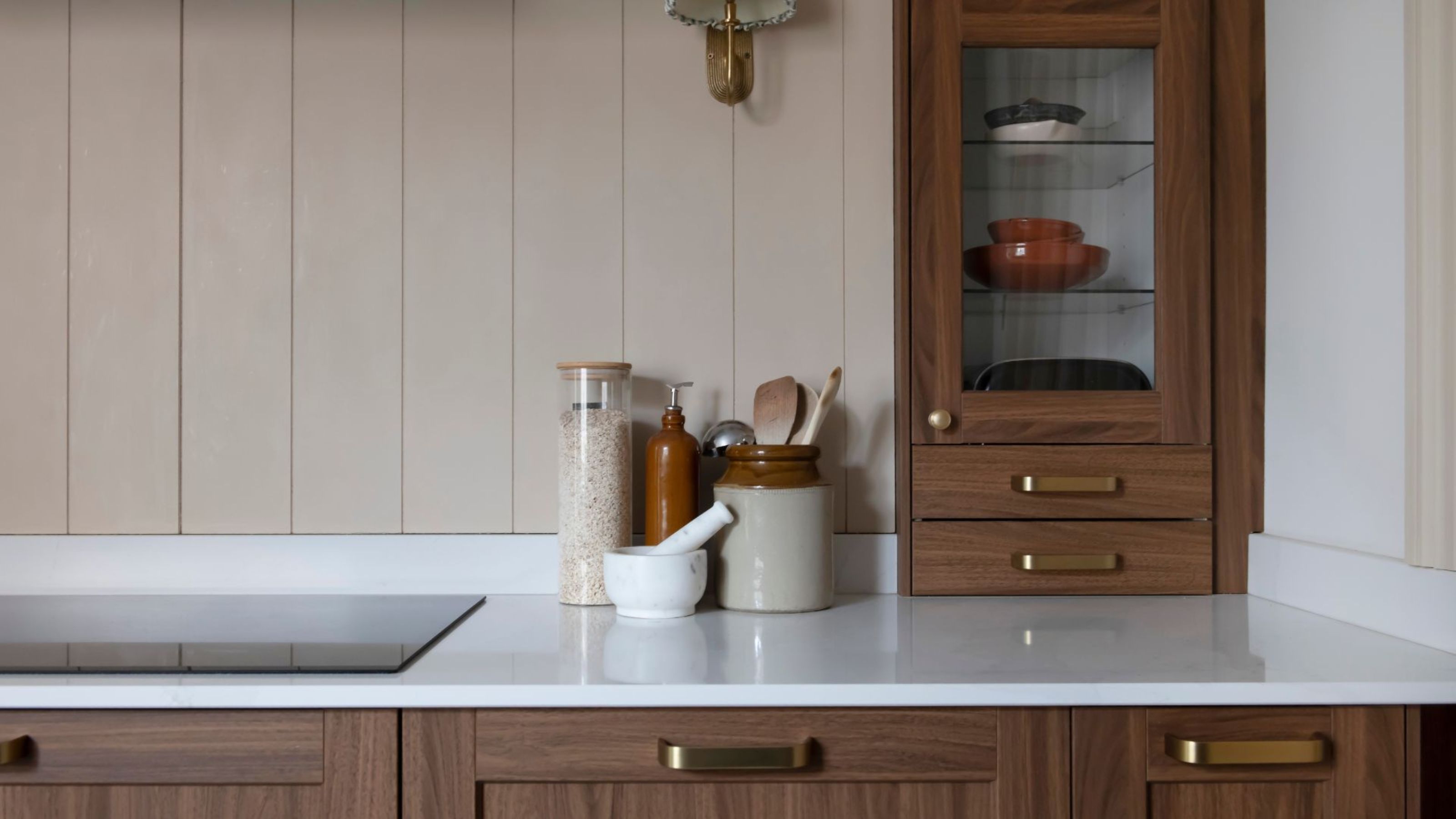 white kitchen counter tops with brown cabinets and induction hop, assorted jars of salt and other kitchen tools