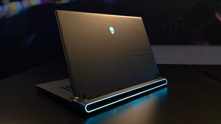 Alienware m17 R5 gaming laptop open with lid facing the camera and blue light from laptop reflecting on table